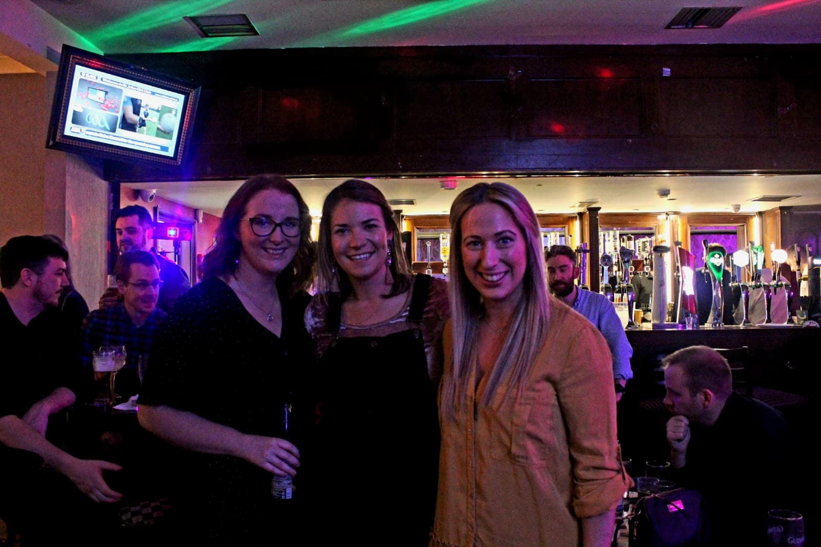 Three women at the PDI under purple and green ambient light